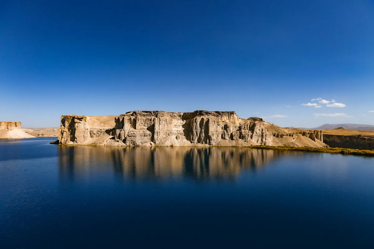 Panoramic view of Band-e Amir lake with limestone cliffs in Bamyan, Afghanistan under clear blue sky.