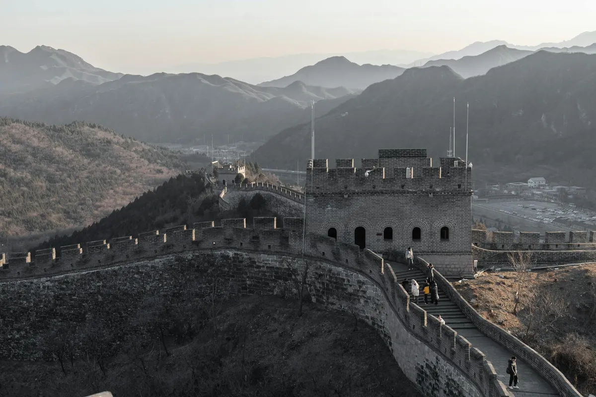 Majestic view of the Great Wall of China winding through mountains at sunset with few visitors.