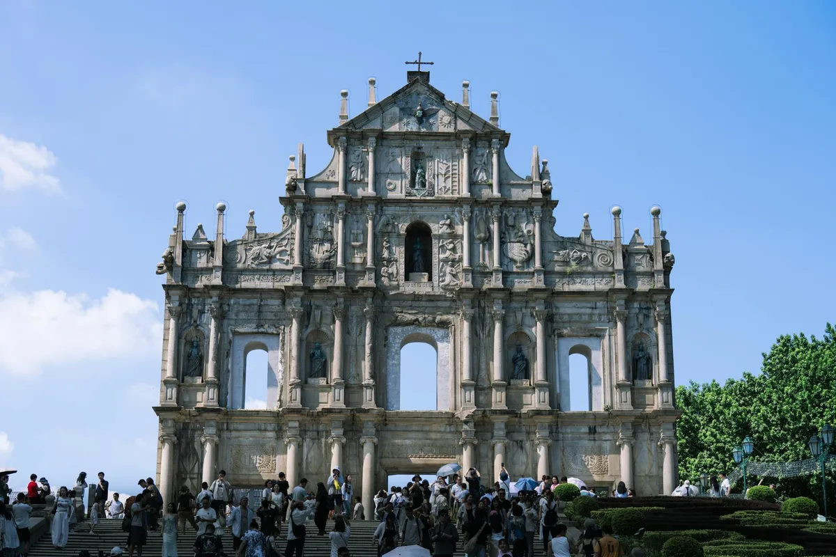 Historic Ruins of St. Paul's in Macau, captured under clear skies with visitors exploring the landmark.