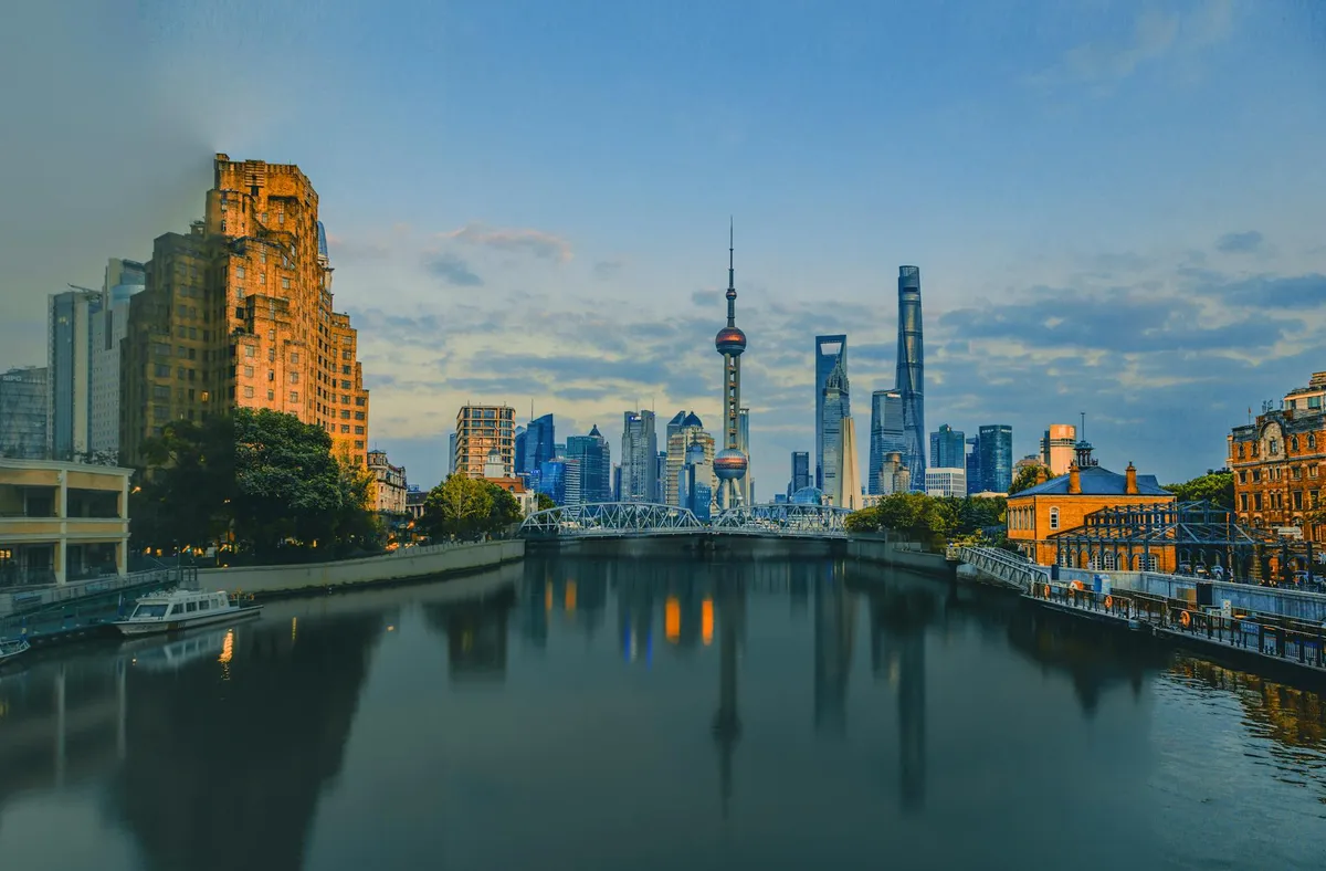 Scenic view of the Shanghai skyline at sunset with the iconic Oriental Pearl Tower reflected in the Huangpu River.