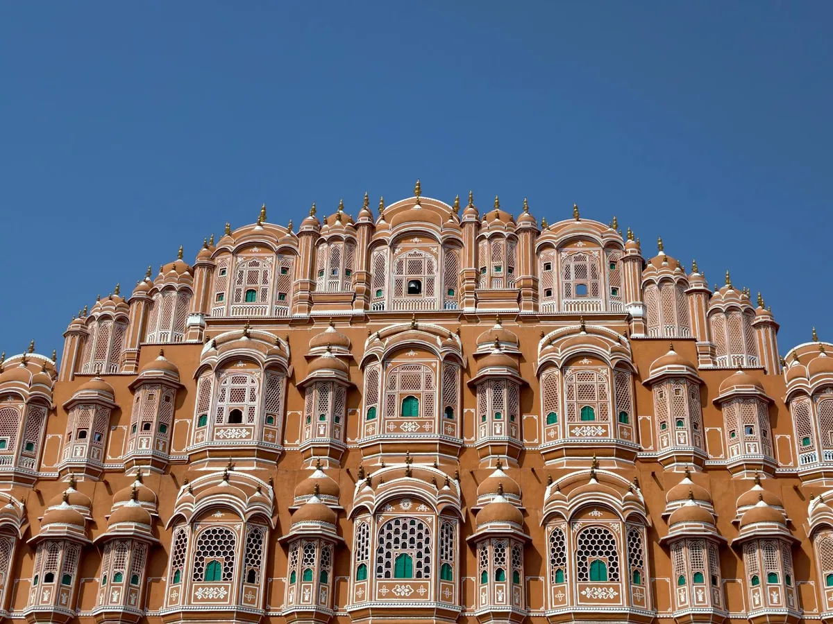 A stunning view of Jaipur's iconic Hawa Mahal with its intricate architecture against a clear blue sky.