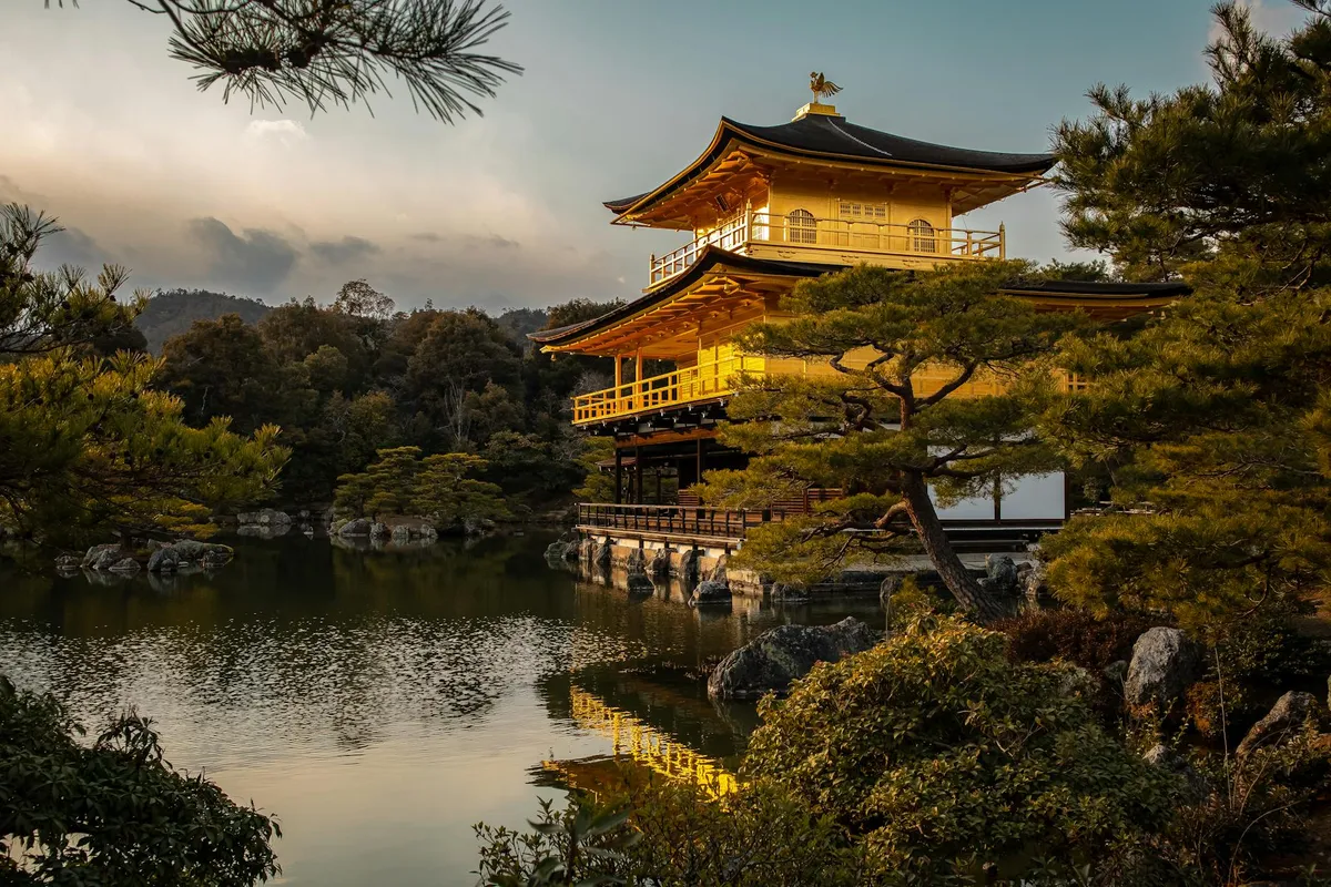 Stunning view of Kinkaku-ji reflected in a serene pond under the warm sunset light.