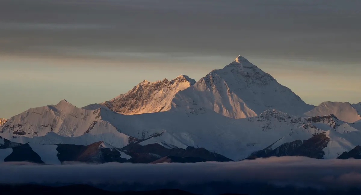 Stunning sunrise view of Mount Everest with snow-capped peaks and soft golden sunlight.