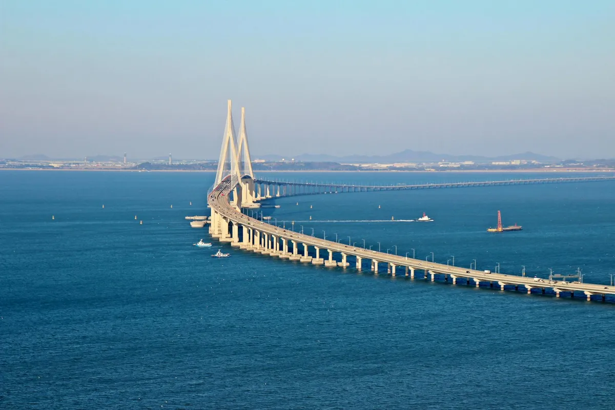 Stunning aerial view of Incheon Bridge spanning across blue ocean waters under a clear sky.