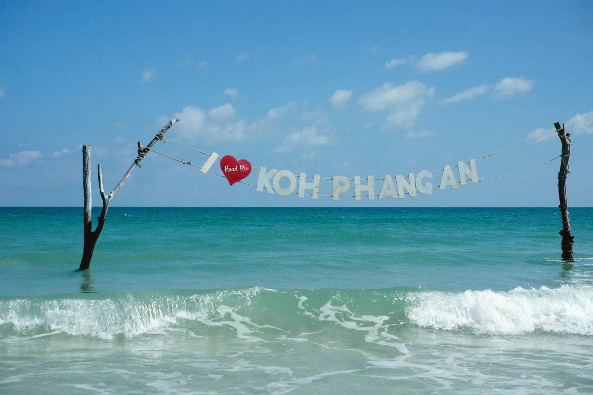 Beautiful seascape of Koh Phangan with ocean waves and a welcoming sign, perfect for travel promos.