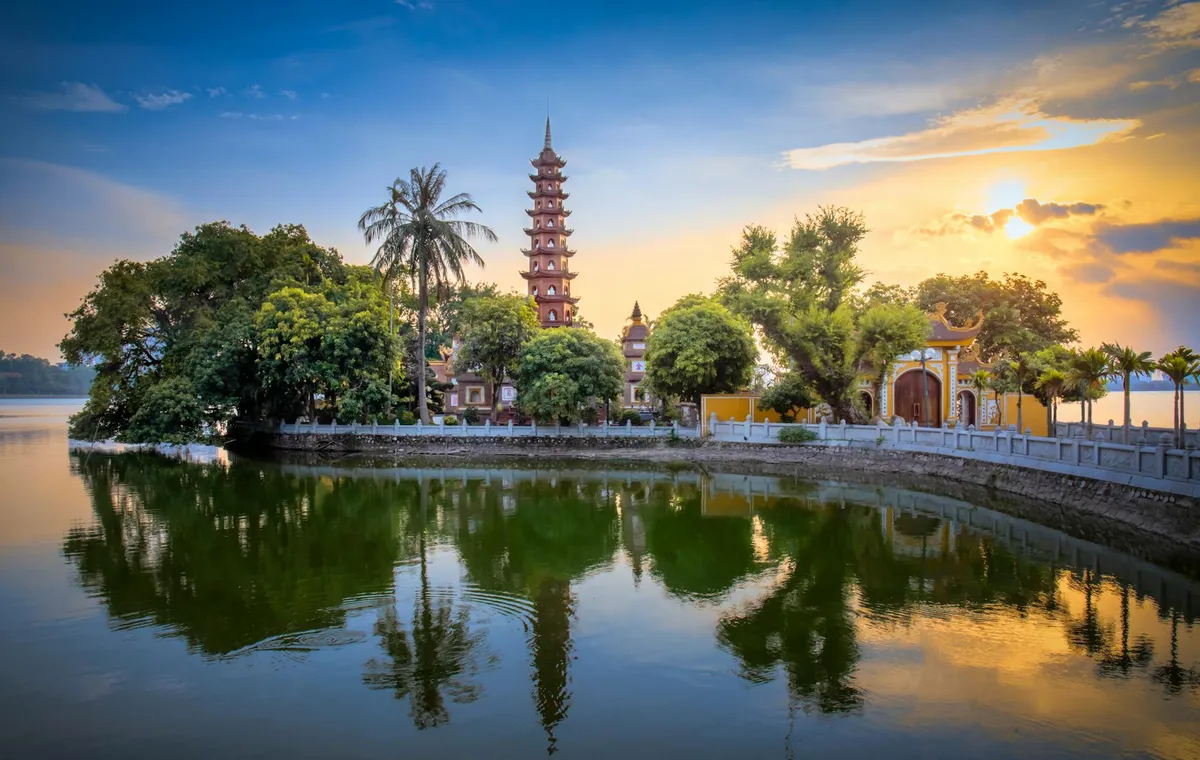 Stunning sunset view of Tran Quoc Pagoda reflecting on West Lake, Hanoi, Vietnam.