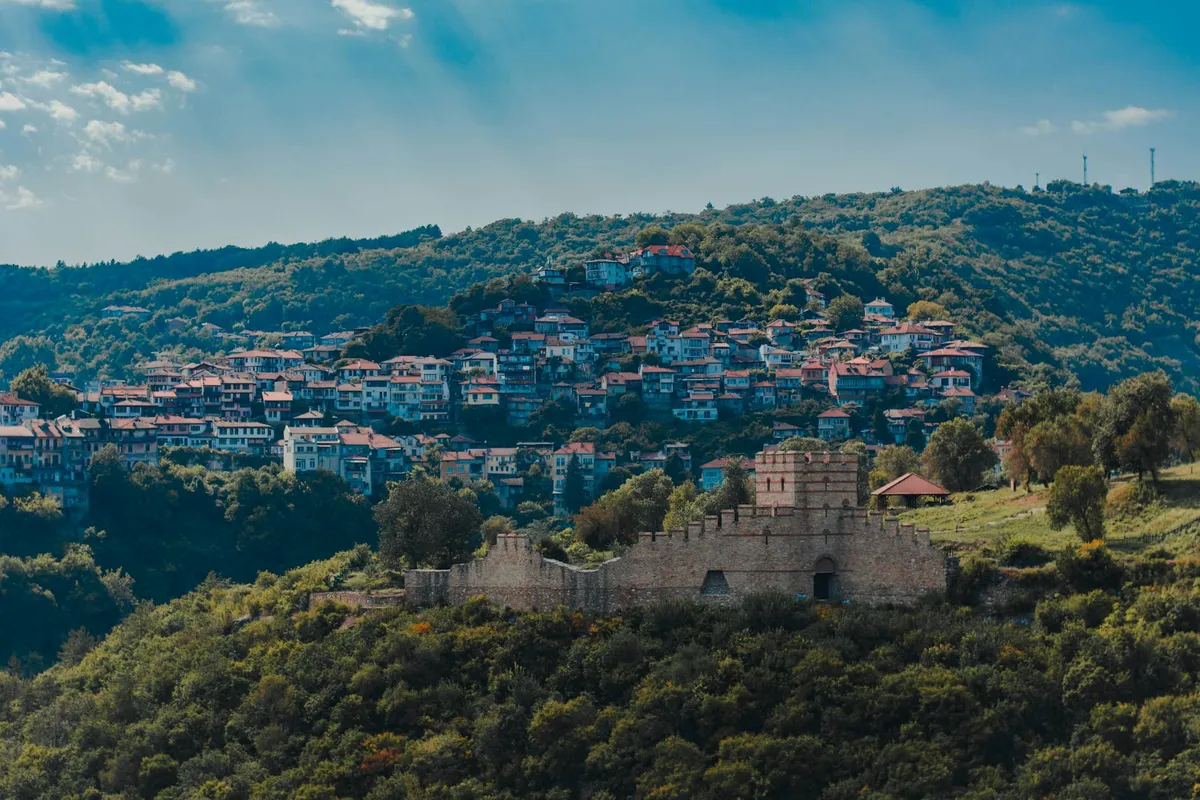 A stunning aerial view of Veliko Tarnovo, Bulgaria, showcasing a historic fortress and vibrant hillside houses.