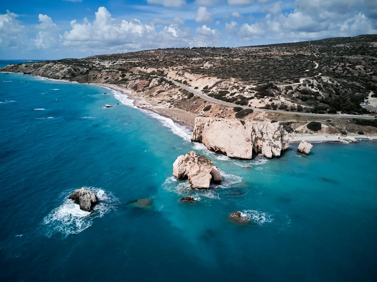 Stunning aerial shot of Petra tou Romiou, Aphrodite's Rock, surrounded by turquoise seas in Kouklia, Cyprus.