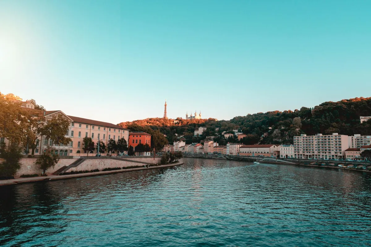 Lyon cityscape with river, buildings, and famous landmarks at sunset.