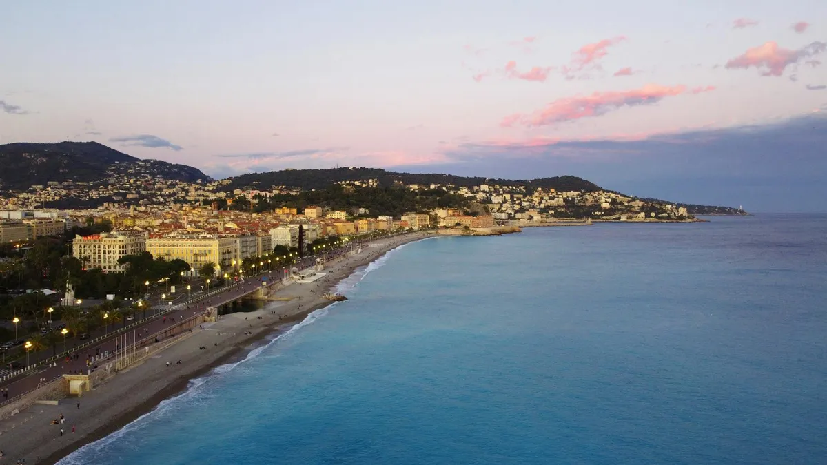 A breathtaking aerial view of Nice, France, with the Promenade des Anglais and Mediterranean Sea at sunset.