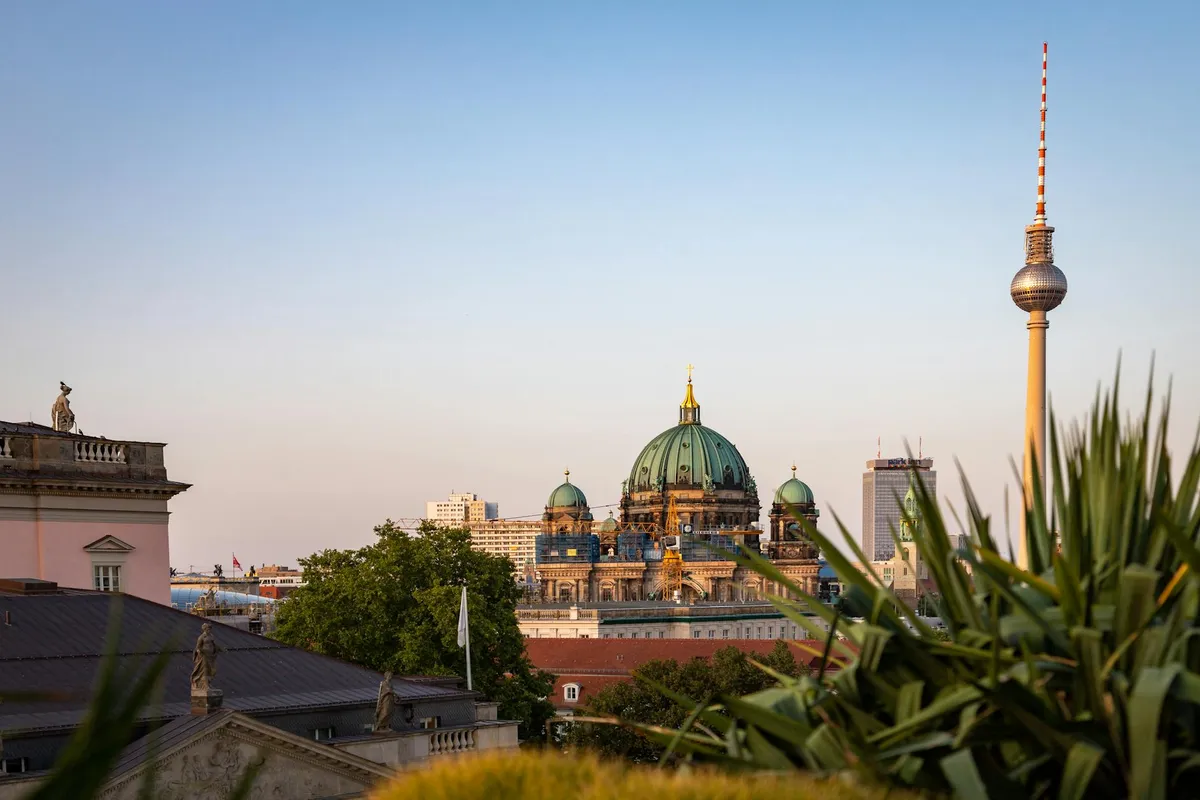 Beautiful view of the Berlin Cathedral and Fernsehturm under a colorful sunset sky.