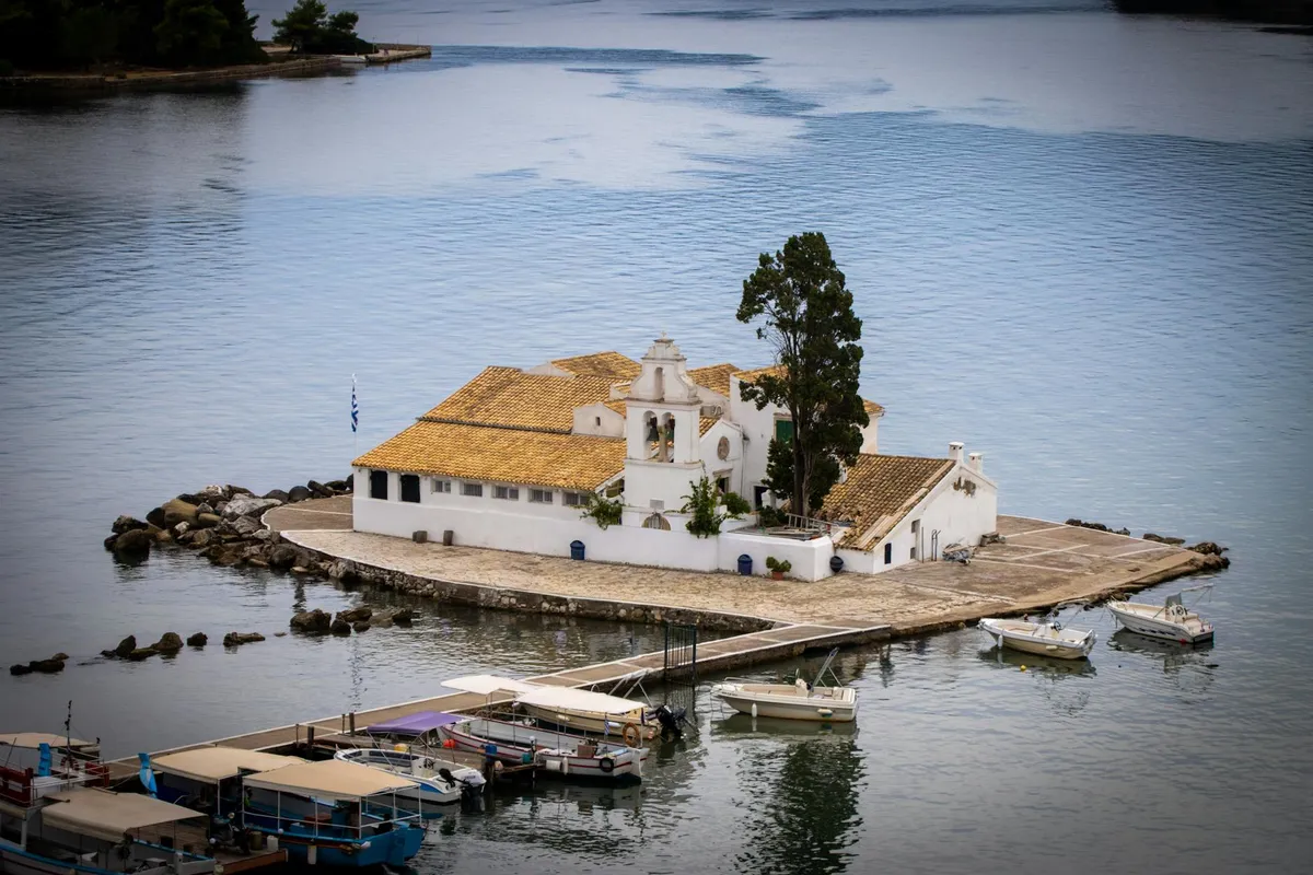 Stunning aerial view of the historic Kanoni Monastery on a small island in Corfu, Greece, surrounded by tranquil waters.