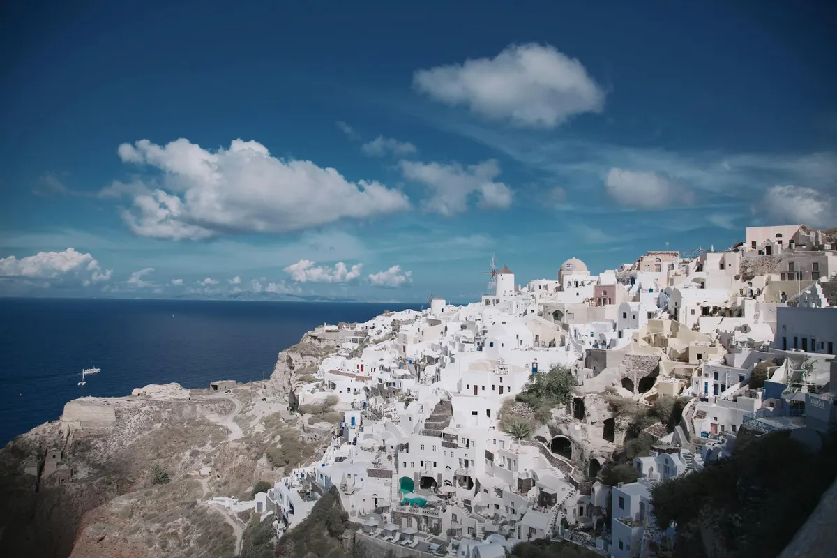 Stunning panoramic view of Oia, Santorini showcasing iconic whitewashed architecture by the sea under a vibrant sky.
