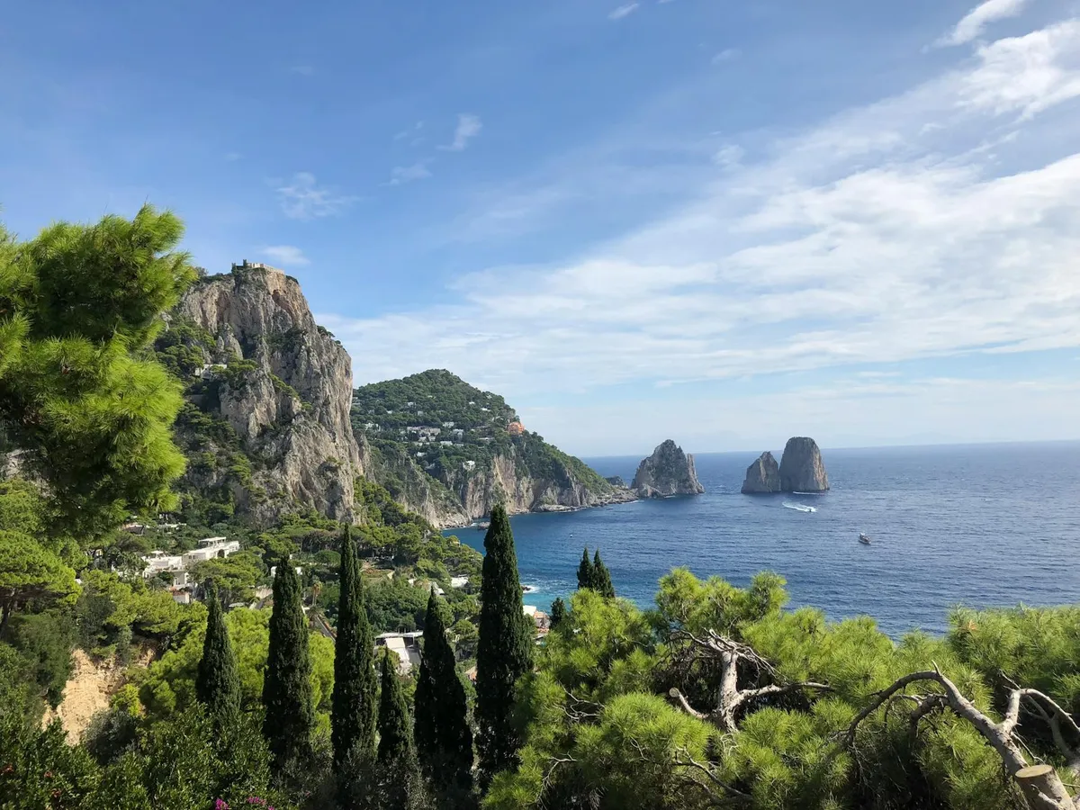 Discover the breathtaking beauty of Capri's coastline, featuring the famous Faraglioni rock formations and lush greenery.