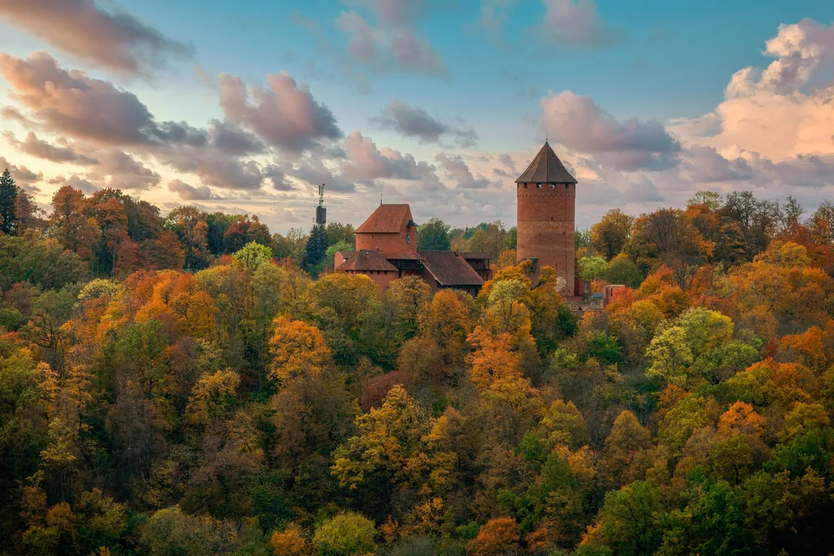 Breathtaking aerial view of Turaida Castle surrounded by vibrant autumn foliage in Sigulda, Latvia.