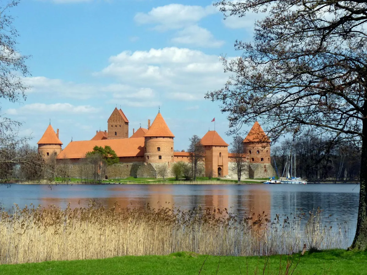 A stunning view of Trakai Island Castle reflecting in the serene lake on a sunny day.