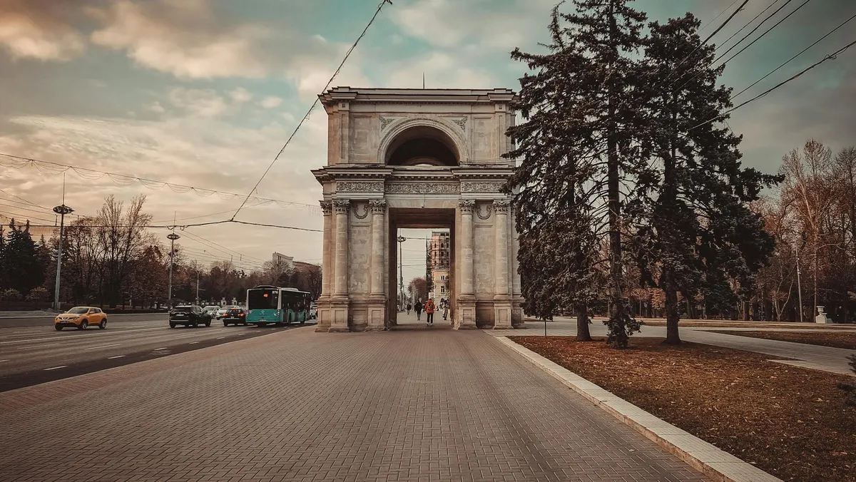 Historic Triumphal Arch in Chișinău, Moldova. A picturesque monument surrounded by a city street scene.