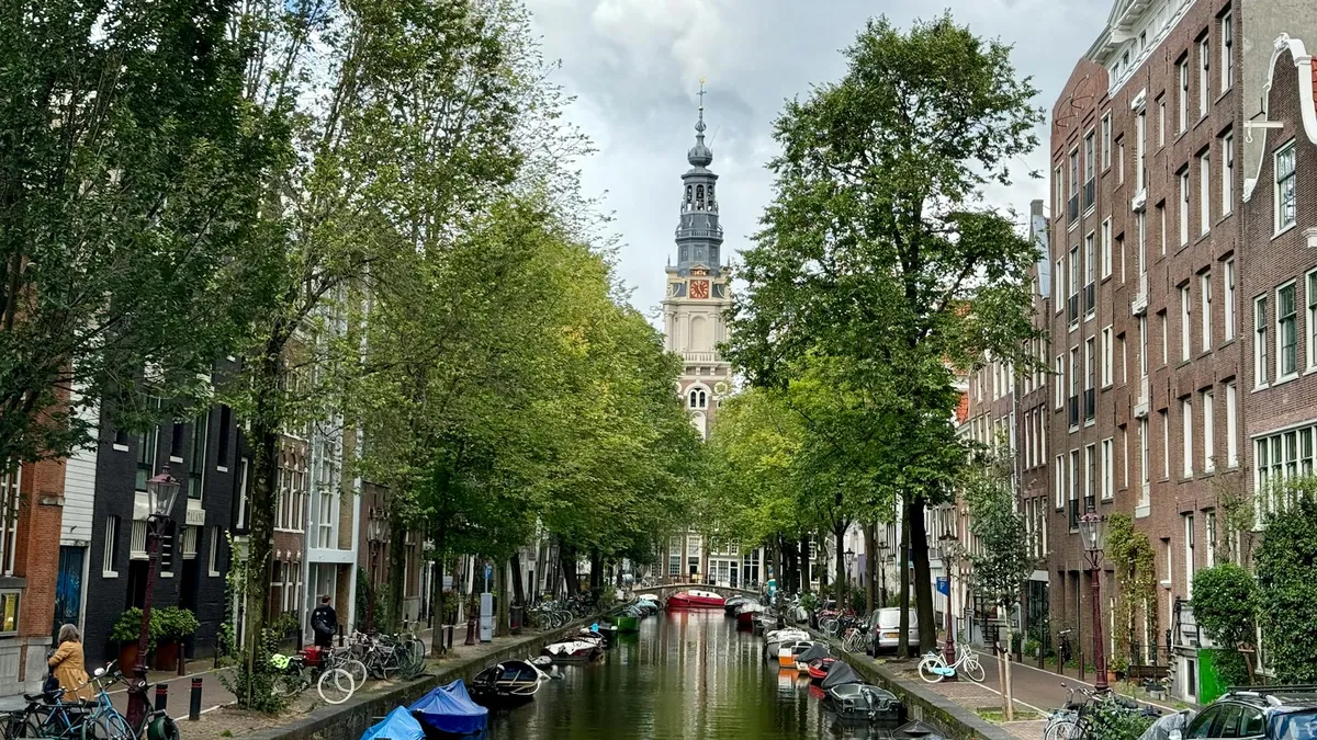 Charming view of Amsterdam canal lined with bicycles and boats, featuring the iconic Westerkerk tower.