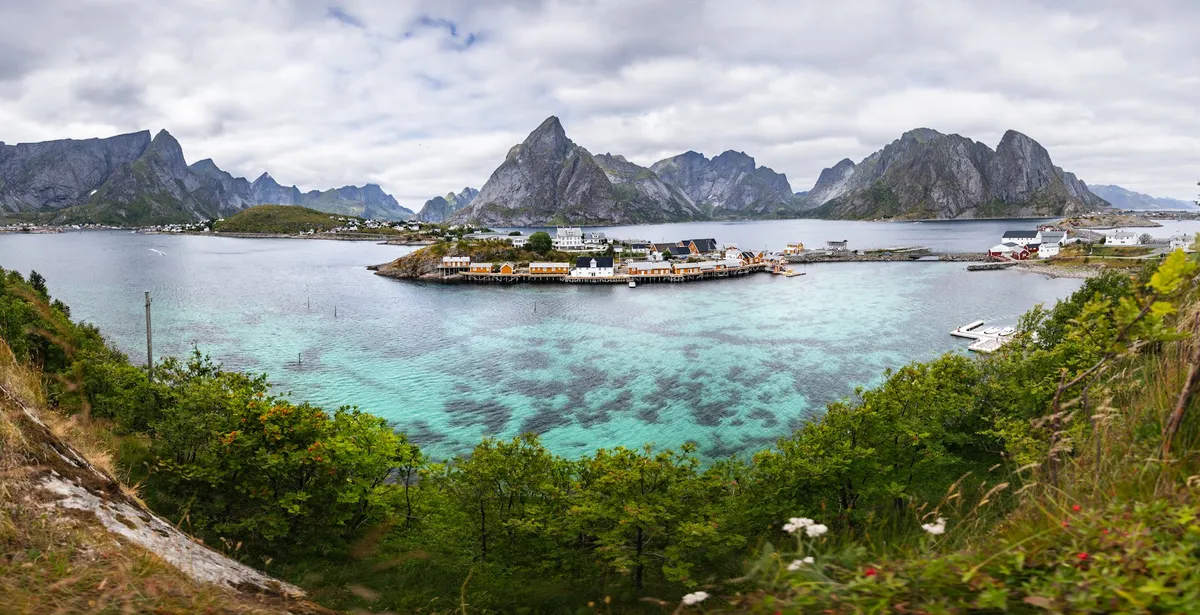 Breathtaking panoramic view of Reine village, Lofoten Islands with turquoise waters and stunning mountain backdrop.