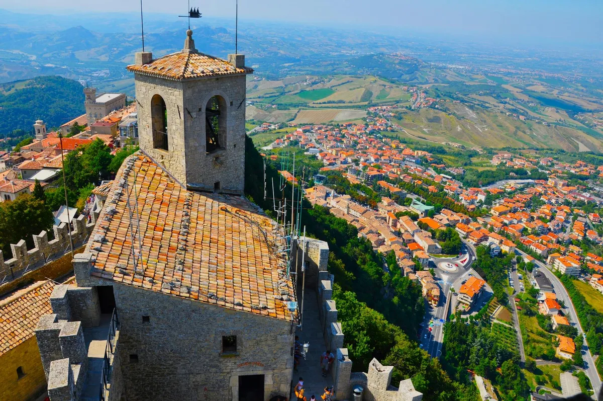Breathtaking aerial photo of Guaita Tower and San Marino cityscape under clear skies.