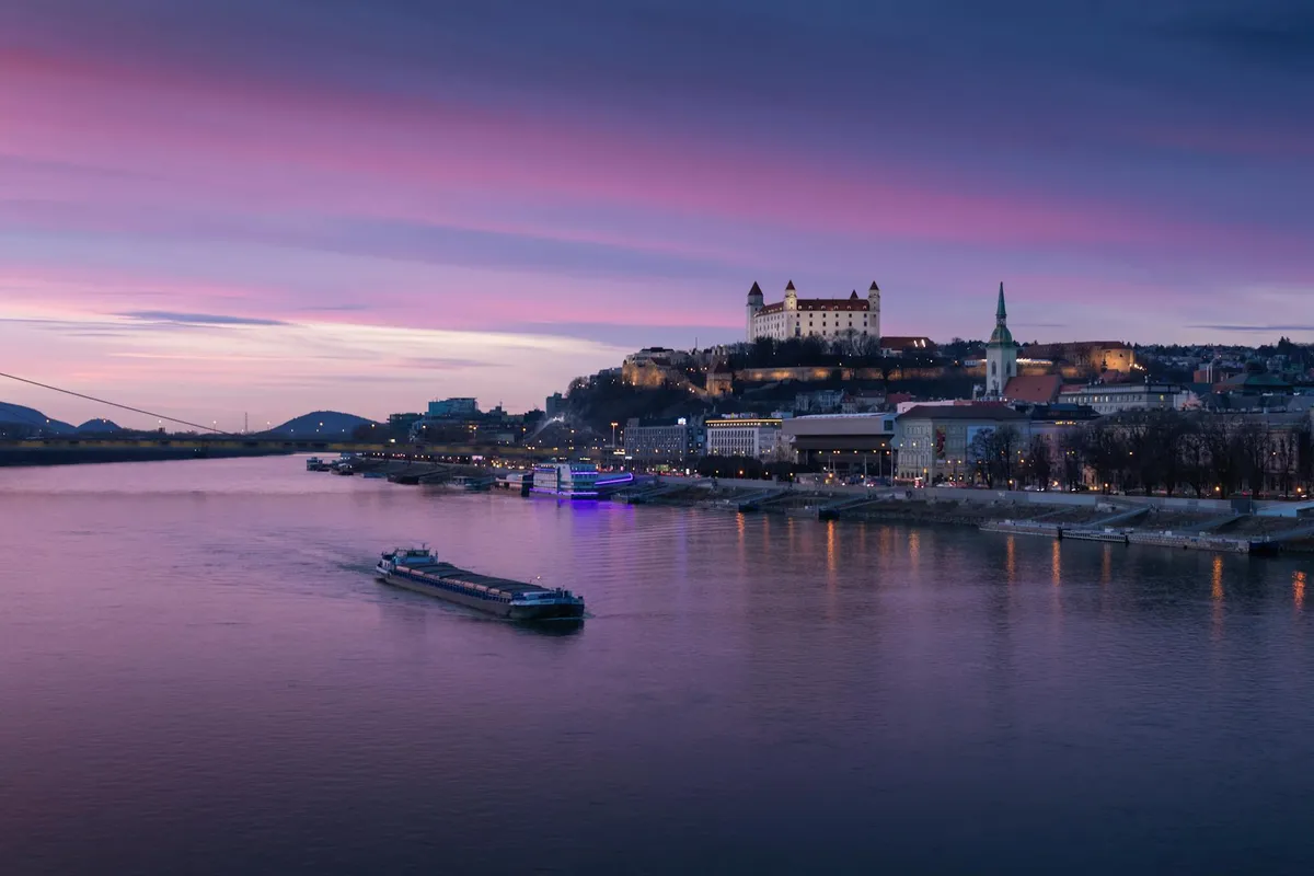 A picturesque view of Bratislava Castle and Danube River at sunset, showcasing Slovakia's scenic cityscape.