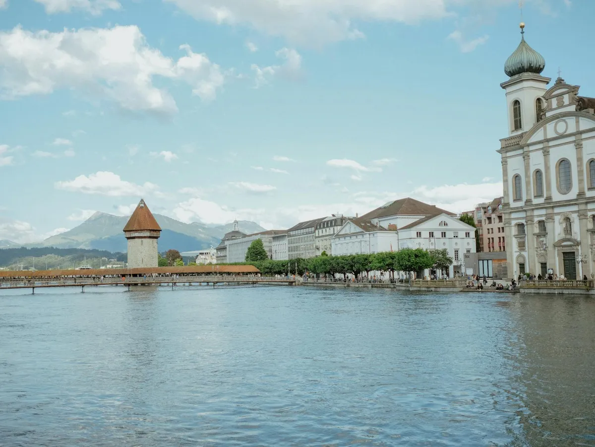 Picturesque view of Chapel Bridge and Water Tower in Luzern, Switzerland with mountains in the background.