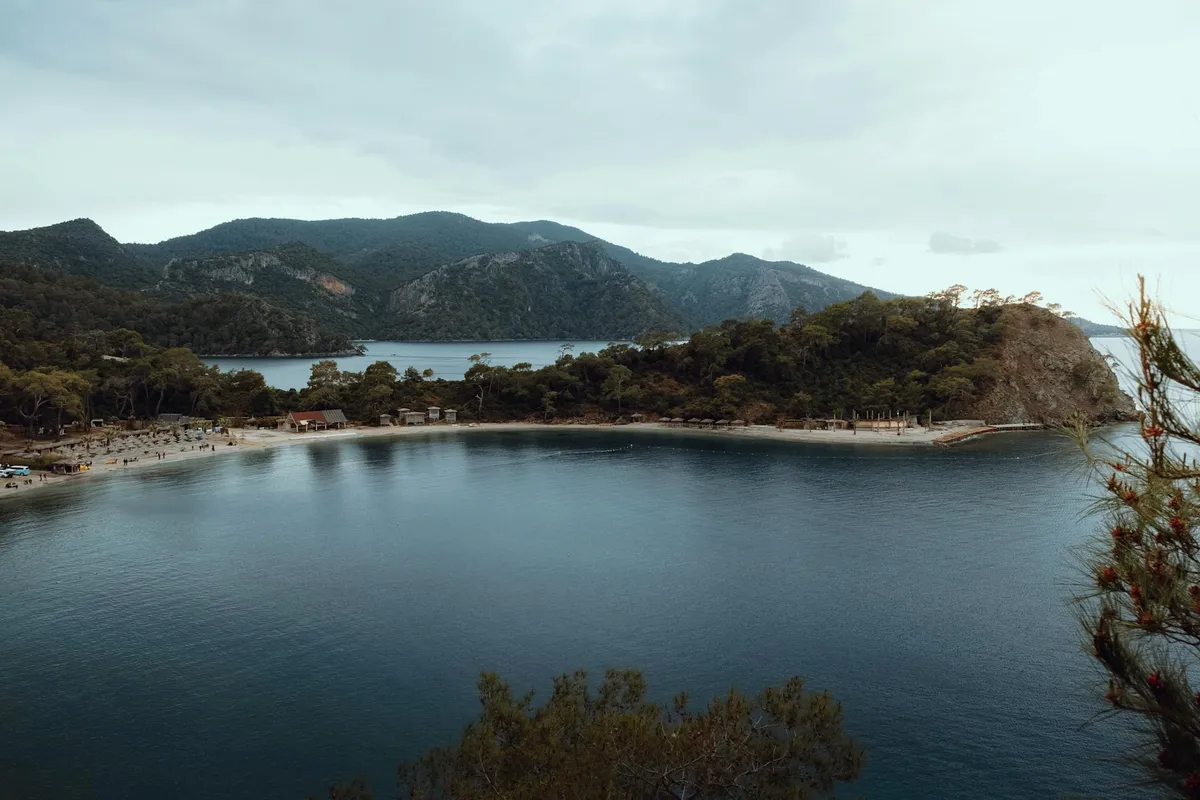 Stunning aerial shot of Ölüdeniz Lagoon with lush hills and serene waters in Fethiye, Türkiye.